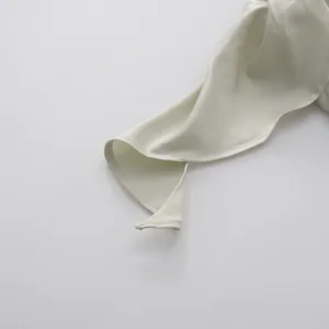 Detailopname van de gladde satijnen stof en stiksels op een jurk met een gedrapeerde halslijn