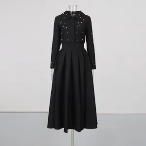 Front detail of black cropped jacket and pleated skirt set with elegant pearl accents