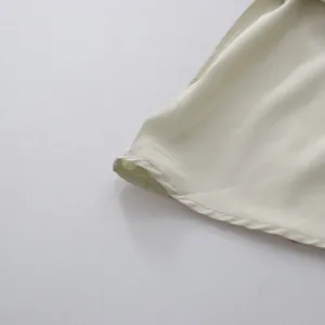 Detailopname van het fijne stiksel en de gladde satijnen stof van een crème cocktailjurk.