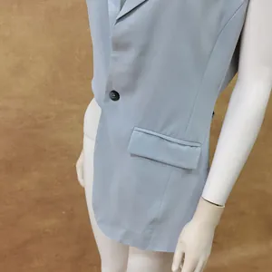 Nahaufnahme einer hellblauen ärmellosen Weste mit einem schwarzen Knopf und Taschendetail