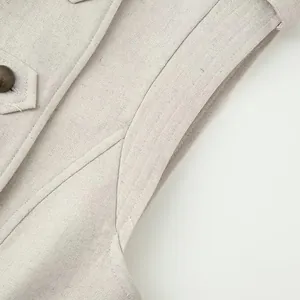Close-up detail of apricot linen vest dress showing armhole stitching and vintage button