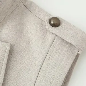 Macro view of apricot linen vest dress shoulder epaulet and vintage bronze button detail