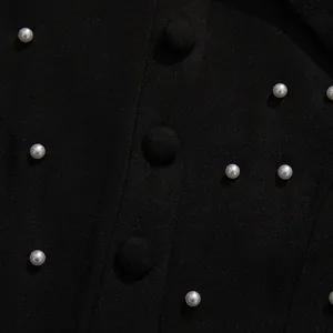 Close-up of elegant black fabric with pearl accents and matching buttons for women's suit.