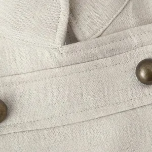 Detailed view of apricot vest dress fabric with bronze buttons and stitching