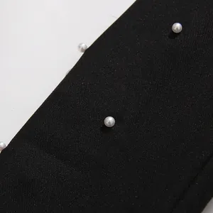 Close-up macro detail of premium black fabric featuring elegant white pearl embellishments