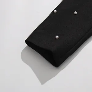 Close-up of elegant black sleeve with delicate pearl embellishments in retro style.