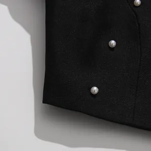 Close-up detail of white pearl buttons on high-end black textured fabric vintage set