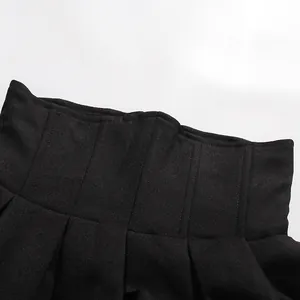 Close-up view of a high-waisted black pleated skirt with fine textured fabric