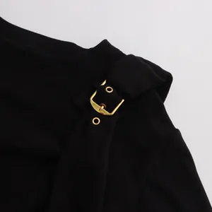 Primo piano del dettaglio della fibbia in metallo dorato su una t-shirt nera a maniche lunghe