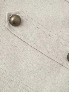 Close-up detail of apricot sleeveless vest dress featuring a vintage bronze metal button