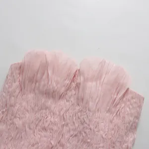Dettaglio del top a fascia plissettato rosa con bordi a balze e trama di tessuto a nido d'ape.