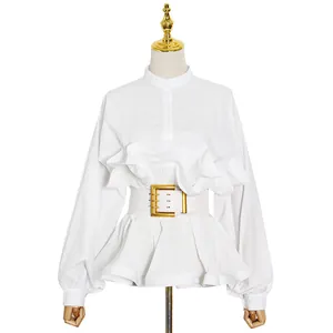 Elegant detail view of a white long-sleeve shirt featuring ruffles and a gold-buckle belt.