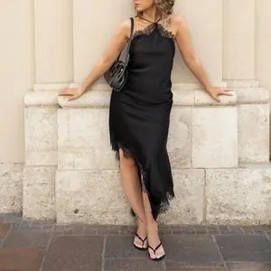 Detail of elegant black satin halter dress with asymmetrical lace trim and slim fit design
