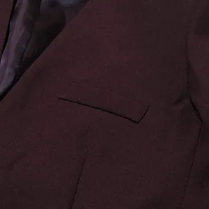 Close-up detail of burgundy oversized blazer showing welt pocket and fabric texture