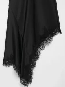 Close-up detail of black satin dress hem with delicate floral lace and asymmetric cut.