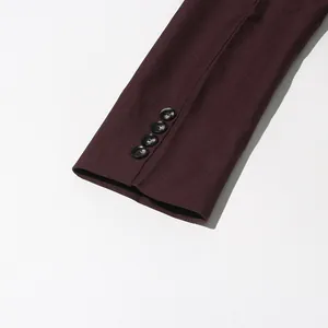 Detailed macro view of a burgundy blazer sleeve featuring four black decorative buttons