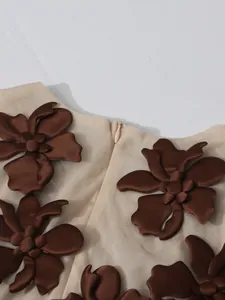Κοντινό πλάνο με καφέ 3D λουλούδια και κρυφό φερμουάρ σε μπεζ γιλέκο.