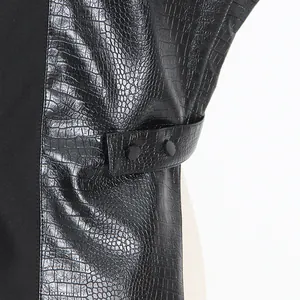 Close-up detail of a black faux leather vest with crocodile pattern and snap strap