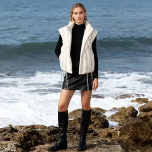 Full shot of white puffer vest with elegant diamond tassel design on a coastal background