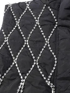 Close-up view of the intricate rhinestone diamond fringe on a black quilted vest detail.