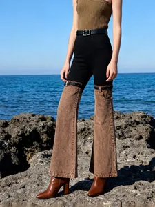 Close-up of high-waisted flared jeans with unique brown denim patchwork design