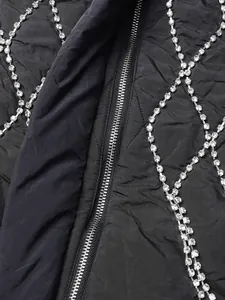 Close-up of black quilted vest with luxury rhinestone fringe and metal zipper detail