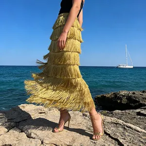 Elegant yellow tiered fringe skirt blowing in the wind by the sea during sunset.