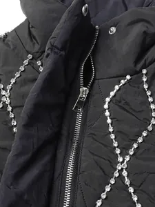 Close-up detail of luxury rhinestone embellishments and silver zipper on black quilted vest