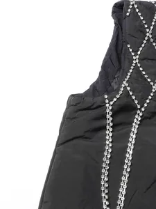 Macro view of a stylish black padded vest featuring luxury rhinestone lattice details.