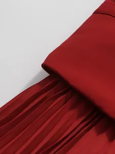 Close-up of elegant red pleated skirt showing high-waisted detail and fine pleats