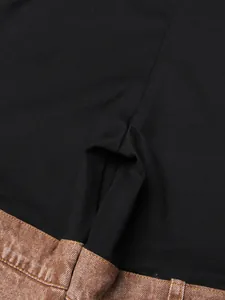 Close-up of patchwork brown denim and black fabric detail on high-waist flared jeans.