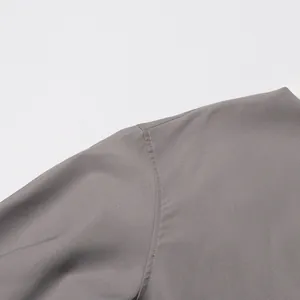 Detailopname van de gladde grijze stof en schoudernaad van deze jas in Japanse stijl