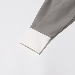 Detailopname van de contrasterende witte manchet op een grijze retro damesjas.