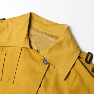 Close-up view of mustard yellow trench coat collar featuring elegant button detail