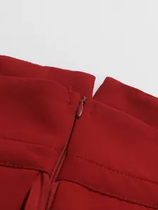 Macro detail shot showing the smooth hidden zipper on a wine red high-waisted pleated skirt.