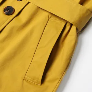 Close-up detail of yellow trench coat pocket and stitching with belt