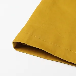 Close-up detail of neat stitching on mustard yellow French style trench coat fabric.