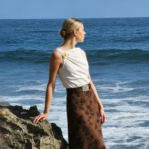Elegante top blanco sin mangas de estilo francés con detalle metálico junto al mar