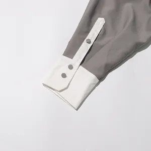 Detailweergave van witte contrastmanchetten en grijze knopen op een vintage lange jas