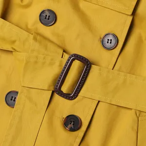Close-up detail of a yellow British style trench coat with belt buckle and buttons