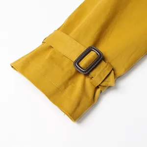 Close-up detail of mustard yellow trench coat sleeve featuring an adjustable buckle strap