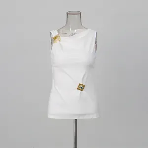 Detalle de un top blanco sin mangas con adornos metálicos dorados y un elegante drapeado.