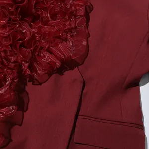 Detailed macro view of burgundy V-neck suit jacket featuring elegant organza ruffle trim