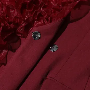 Close-up of burgundy blazer showing ruffle patchwork and metal snap button detail