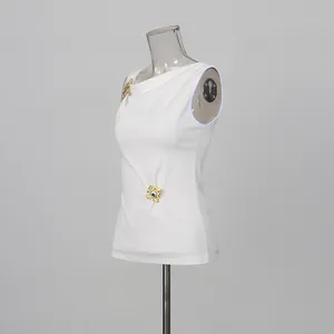 Elegante top blanco sin mangas con diseño plisado y detalles metálicos dorados.