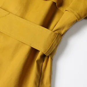 Close-up detail of the mustard yellow belt and loops on a French style trench coat
