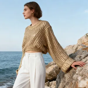 Elegant metallic gold cropped knit sweater featured in an outdoor coastal setting