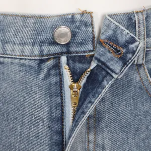 Vue macro détaillée de la fermeture éclair en métal doré et du bouton sur le short en jean