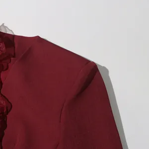Close-up detail of a wine red blazer featuring elegant ruffle trim and V-neckline