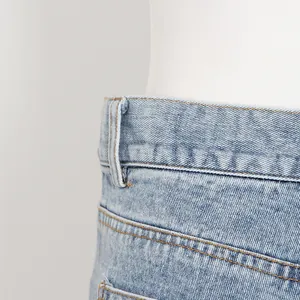 Gros plan sur la taille haute d'un short en jean bleu clair avec coutures jaunes.